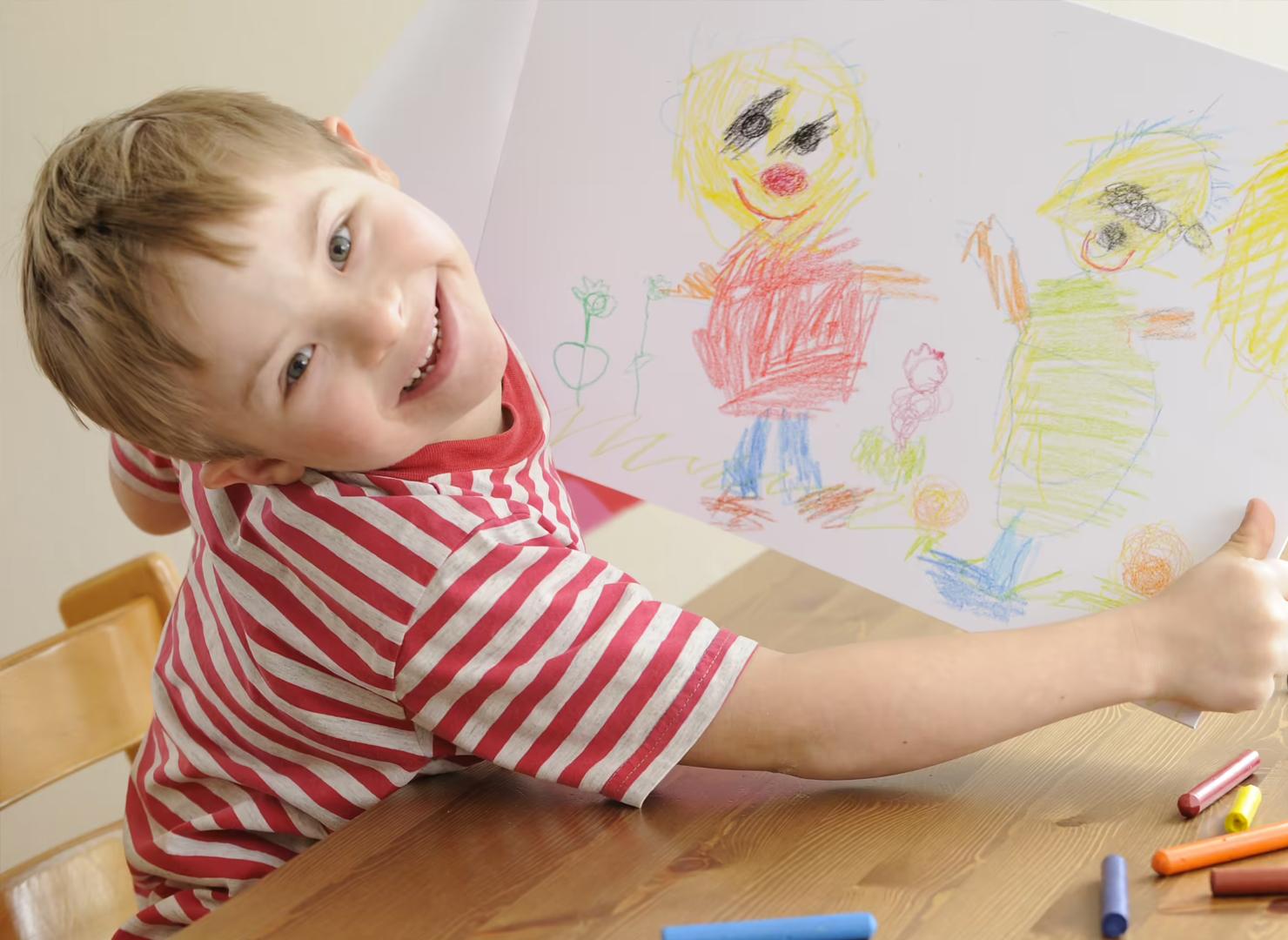 Child dressed in a red and black checked shirt, smiling at the camera with his hands in his pockets.